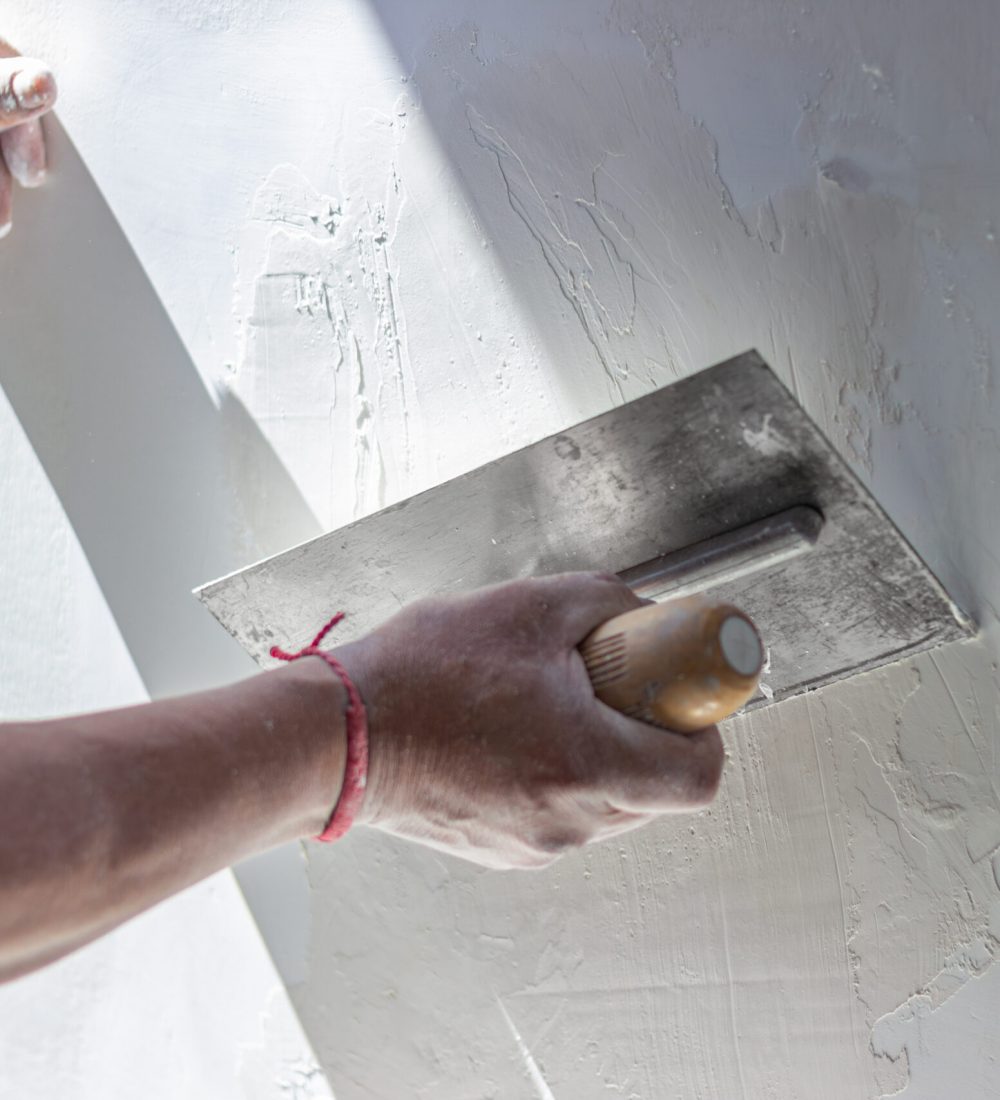 Construction worker skillfully applies plaster to a wall using a trowel, creating a smooth surface during a home renovation or construction project